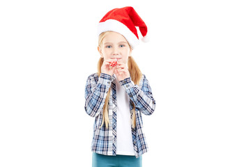 Portrait of sweet little girl in Santa hat blowing into party blower