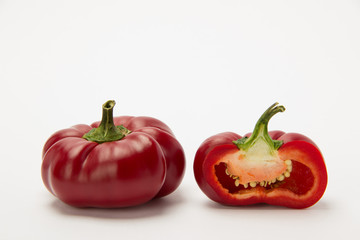 Two ripe red peppers in a cut on a white background