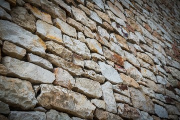Stone wall background of colorful stones with vignetted borders and in perspective view. Selective focus