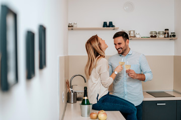 Cute young couple drinking wine in kitchen.