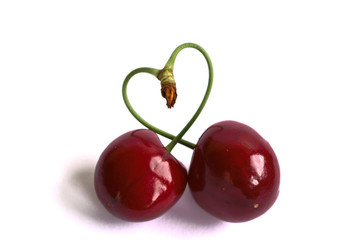 Closeup of cherries with a heart shaped stem on a white background