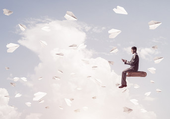 Businessman or student on book and paper planes flying around