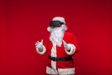 Santa Claus wearing virtual reality goggles, on a red background. Christmas
