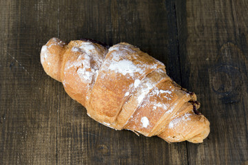 Sweet croissant on a dark wooden surface