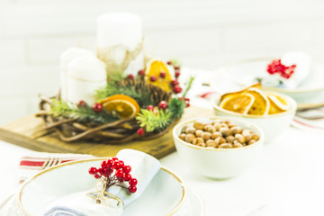 Obraz na płótnie Canvas a table setting for Christmas with a viburnum on a plate and an ornament from a Christmas wreath with candles