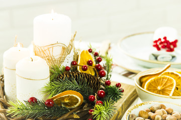 a table setting for Christmas with a viburnum on a plate and an ornament from a Christmas wreath with candles