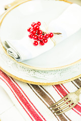 a table setting for Christmas with a viburnum on a plate and an ornament from a Christmas wreath with candles