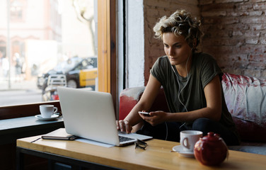 Tomboy girl is reading emails on a screen of a modern portable computer while sitting in a cafe....