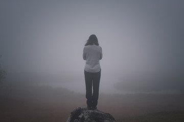Depressive Frau steht an der Klippe und denkt an Selbstmord Depression Nebel Rückansicht