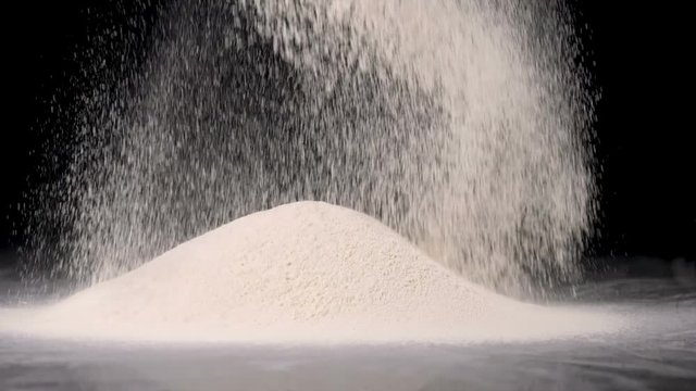 White flour poured on black background in slow motion
