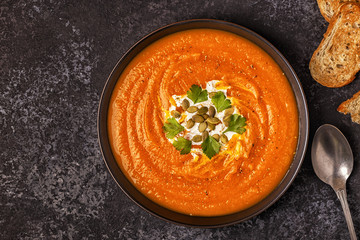 Pumpkin and carrot soup with cream, seeds and parsley.