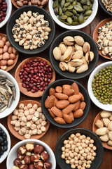 Assortment of beans and lentils in wooden spoon on teak wood background