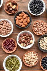 Assortment of beans and lentils in wooden spoon on teak wood background