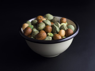 Japanese wasabi crackers in small bowl isolated on black background