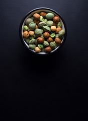 Japanese wasabi crackers in small bowl isolated on black background