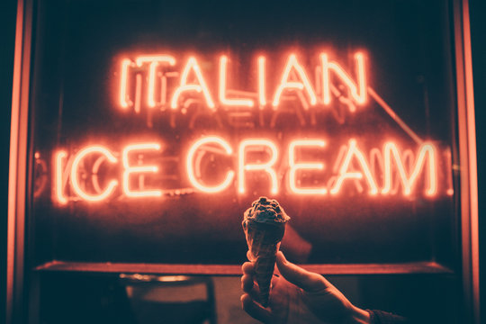Board sign saying Italian Ice Cream with hand holding ice cream cone