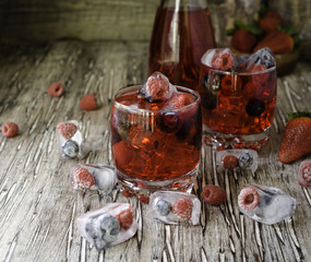 Summer berry lemonade with frozen berries on a wooden rustic table, selective focus