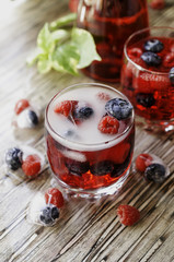 Summer berry lemonade with frozen berries on a wooden rustic table, selective focus