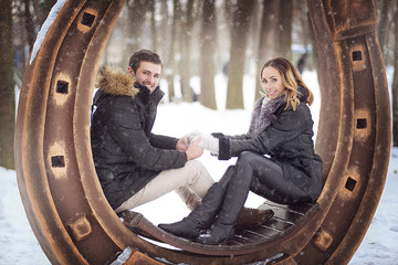 Naklejka na ściany i meble Loving couple sitting and holding hands in the winter during a snowfall