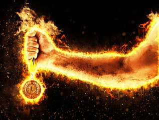 Man's hand in a fire is holding up gold medal. Winner in a competition.