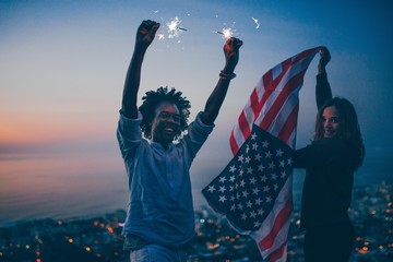 Couple celebrating with sparkler and USA flag at night