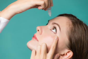 Young woman applying eye lotion.