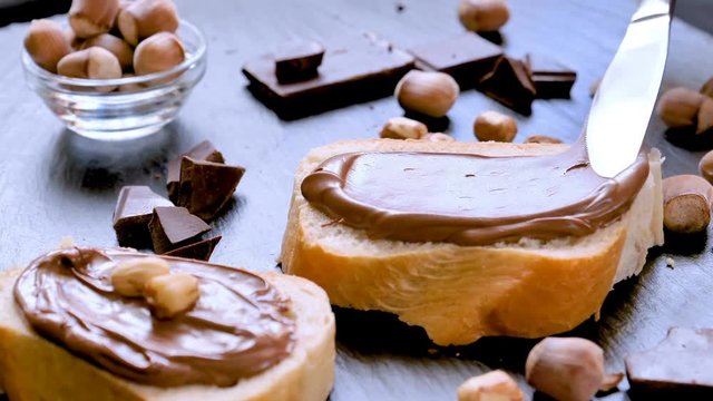 Spreading hazelnut chocolate cream on bread closeup. Delicious breakfast concept.
