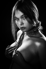 sad young woman with tied neck on black background looking at camera, monochrome