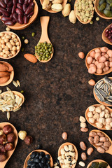 Assortment of beans and lentils in wooden spoon on teak wood background