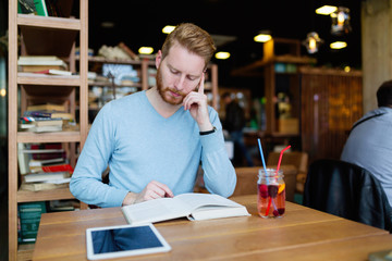 Young handsome student learning in coffee shop