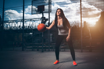 Female basketball player training outdoors on a local court - obrazy, fototapety, plakaty