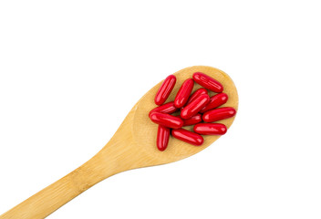 Red vitamins and supplements capsule on wooden spoon isolated on white background with clipping path and copy space for text. Use for advertising design on health content topics