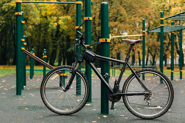 Fototapeta premium Bicycle standing on sports ground in colorful autumn park. Fall season background