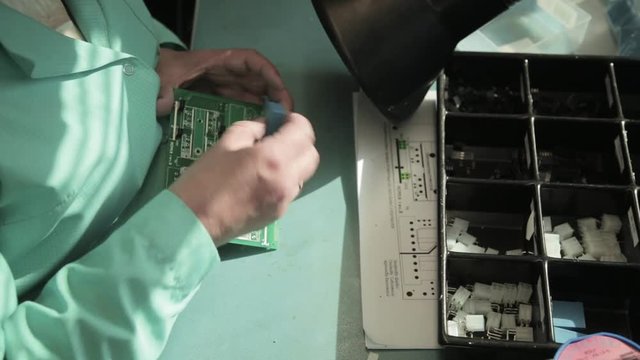 Woman holding pincette and soldering iron instal electronic components on PCB (Printed circuit boards)