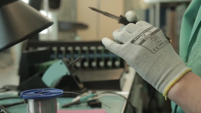 Woman holding pincette and soldering iron install electronic components on PCB (Printed circuit boards)