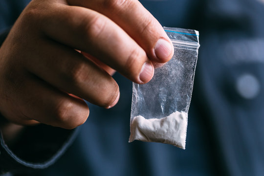 Drug dealer selling drugs junkie. Drug abuse concept and overdose concept. Mans hand holds plastic packet with cocaine powder