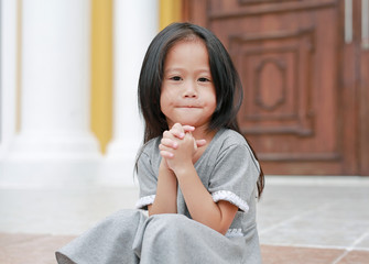 Fototapeta na wymiar Cute little girl praying outdoor with looking camera. Spirituality and religion concept.