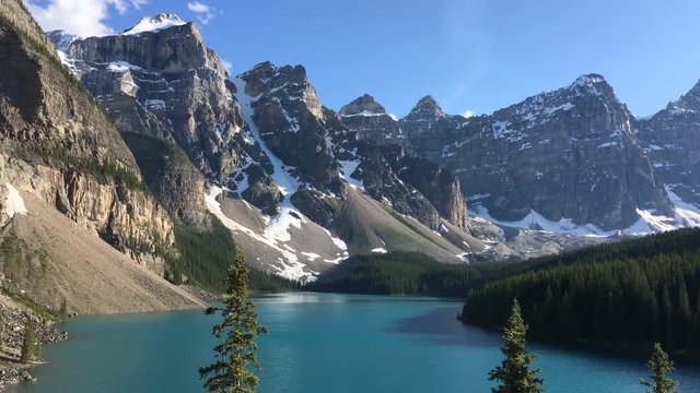 Beautiful turquoise waters of the Moraine Lake with snow-covered peaks above it in Banff National Park, Canada. 4K video.