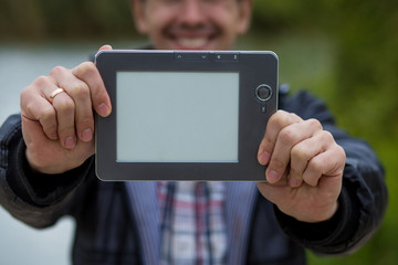 A young man holds a digital tablet in front of him, space for text on screen of tablet