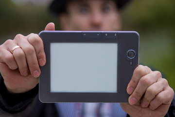 A young man holds a digital tablet in front of him, space for text on screen of tablet