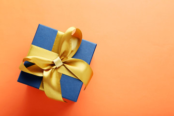 Gift box with ribbon on orange background