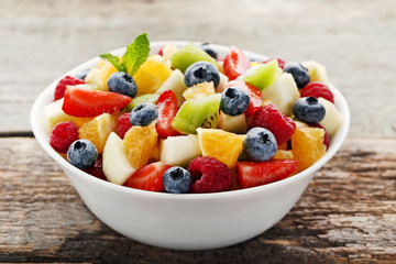 Fresh fruit salad in bowl on grey wooden table