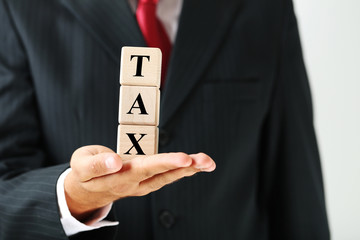 Businessman holding wooden cubes with word Tax