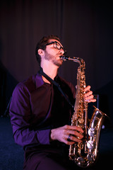 Fototapeta na wymiar Bearded saxophonist in glases. Saxophone on a foreground