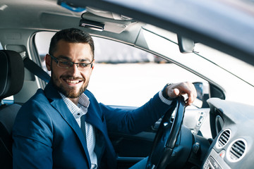 Smiling young man in driving seat of a car