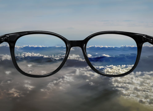 Clear vision through glasses on blue clouds landscape