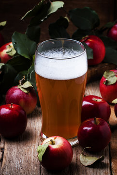 Apple cider in a large beer glass, vintage wooden background, selective focus