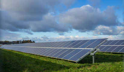 Solar panel or photovoltaic farm on green field with dramatic cloudy sky in North Germany