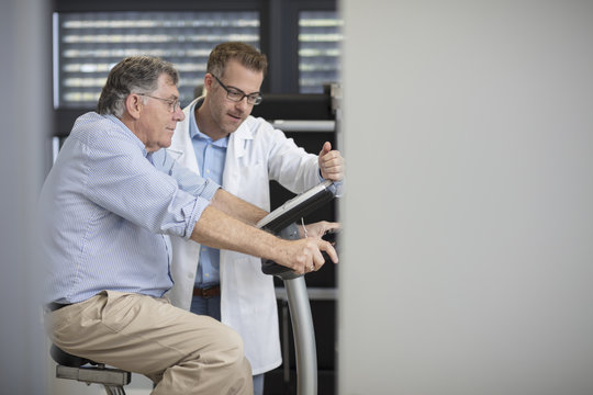Doctor with senior patient on exercise machine