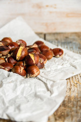 roasted chestnuts in a paper bag on old wooden background. close up and selective focus with copy space